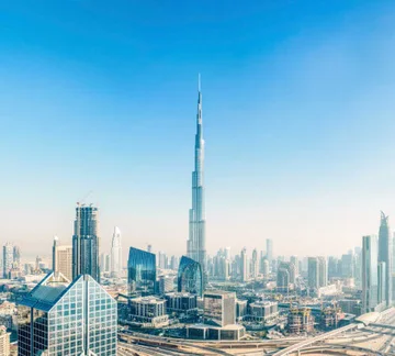 Das Bild zeigt die Skyline von Dubai. Der untere Teil des Bilds zeigt viele Hochhäuser, in der Mitte ist der Burj Khalifa. Der obere Teil des Bilds zeigt den blauen Himmel.